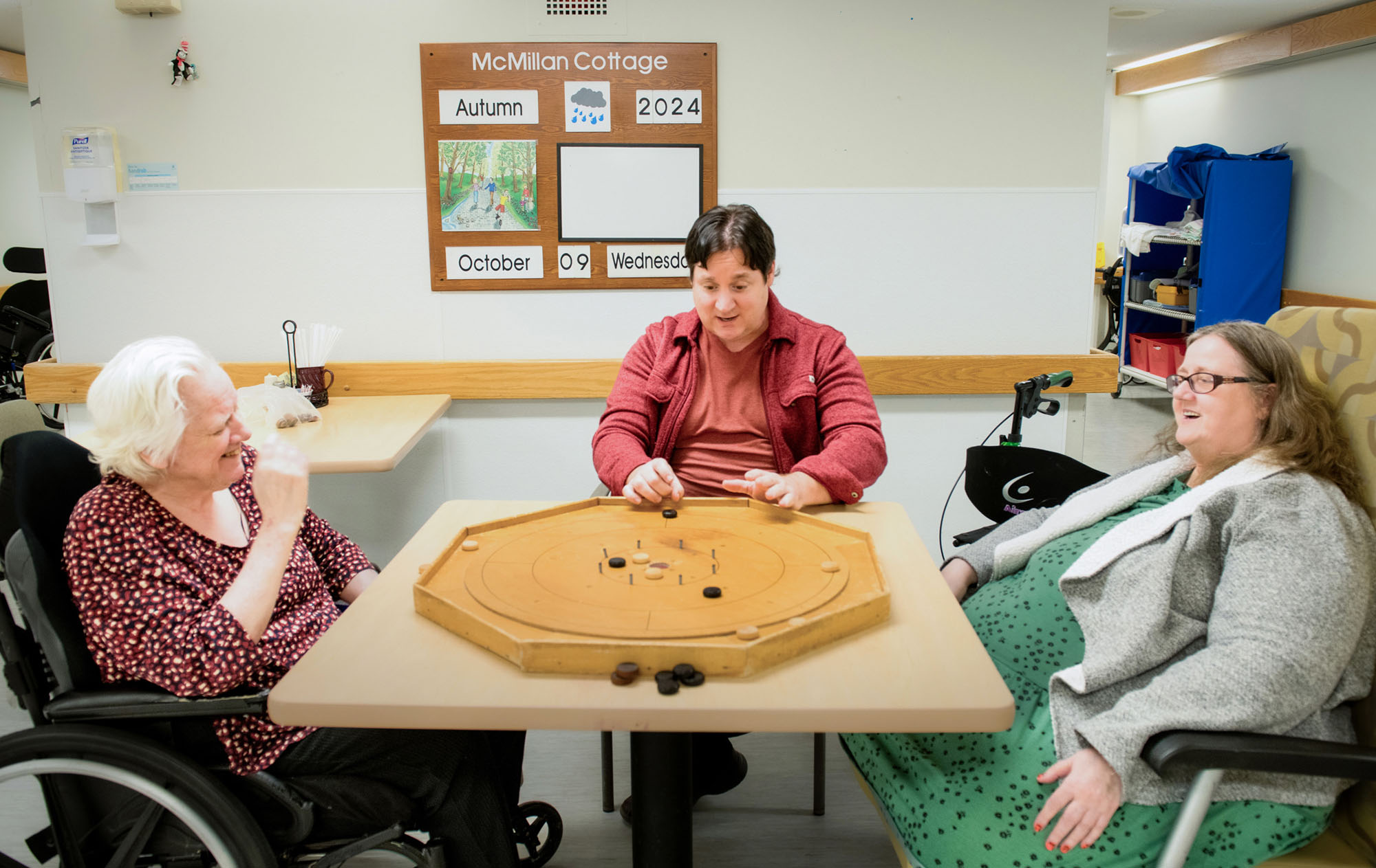 GPL volunteer sitting at a table with two residents.