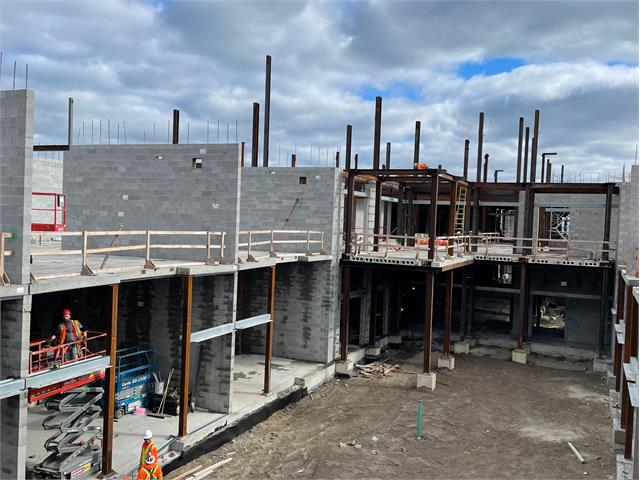 Facility under construction with cement walls and metal supportive beams exposed.